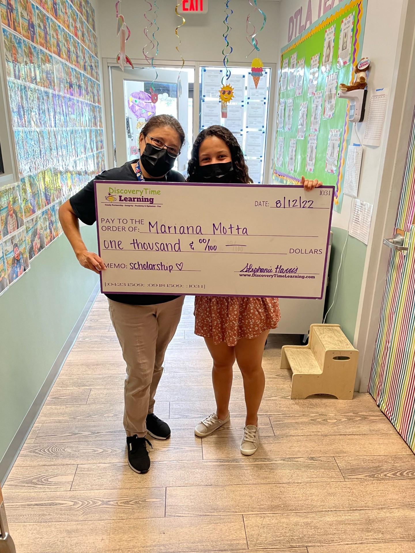 Ms. Stephanie presenting a Discovering Greatness scholarship check to recipient Mariana Motta at Discovery Time Learning Center